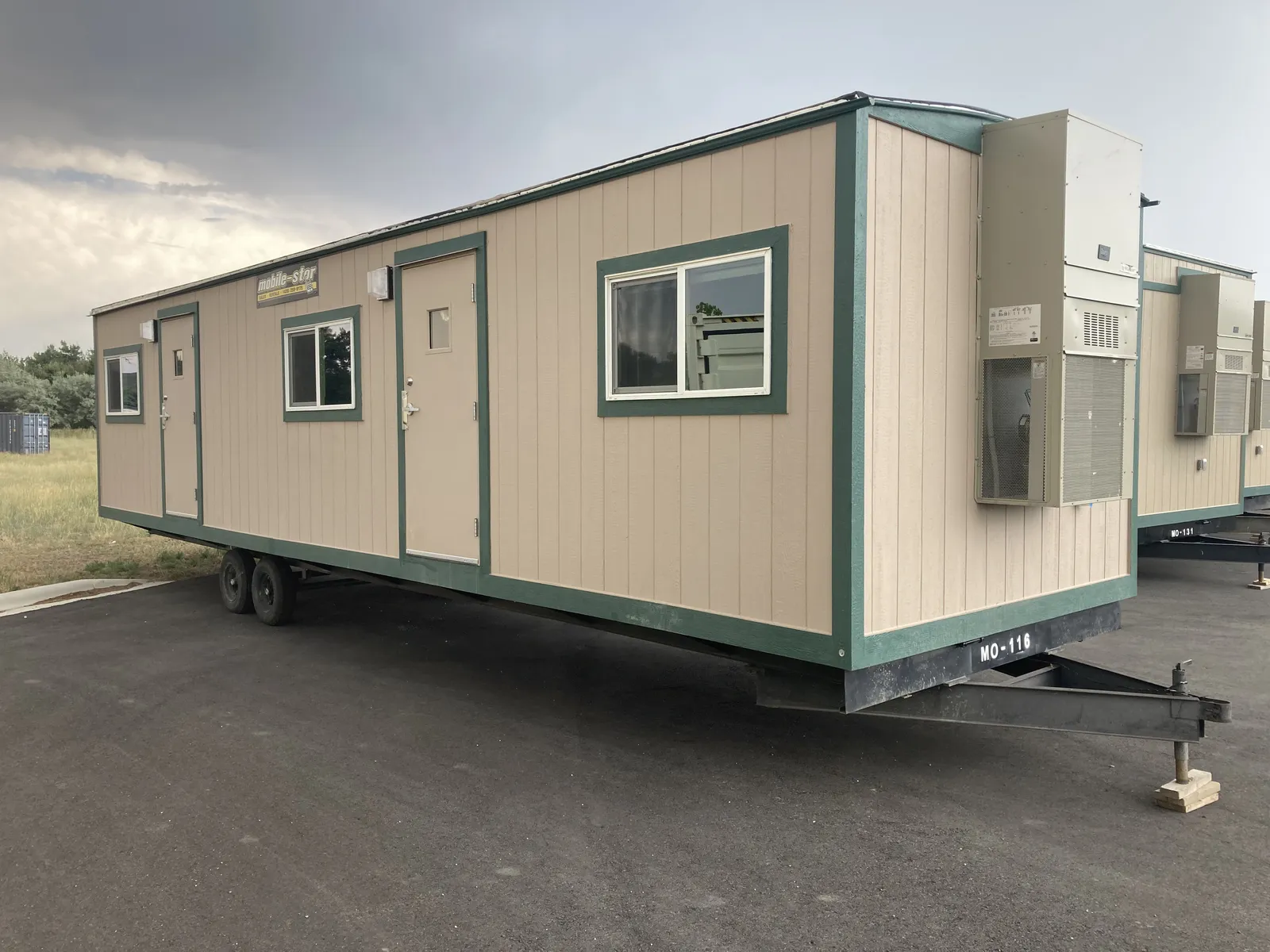 MO-116 Mobile-Stor office trailer with two entrances, windows, green trim, and tandem axles
